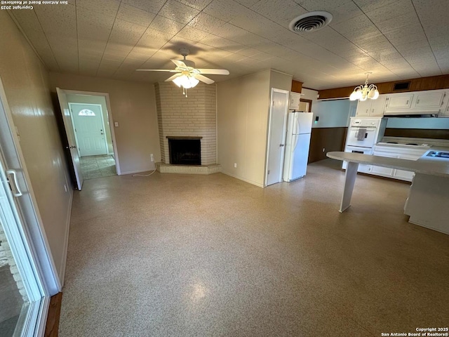 unfurnished living room featuring light speckled floor, a fireplace, visible vents, baseboards, and ceiling fan with notable chandelier