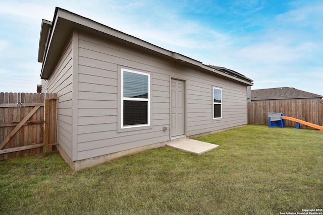 rear view of house featuring a lawn and fence