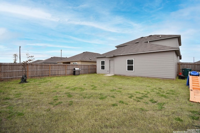 rear view of property with a fenced backyard and a yard