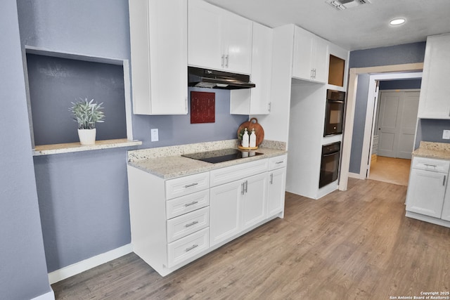 kitchen with light stone counters, white cabinets, light wood-type flooring, under cabinet range hood, and black appliances