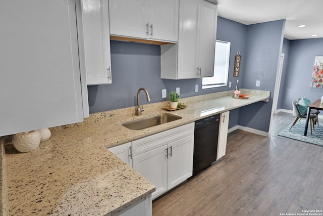 kitchen with black dishwasher, white cabinetry, a sink, and wood finished floors