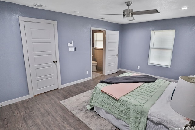 bedroom with visible vents, ensuite bathroom, baseboards, and wood finished floors