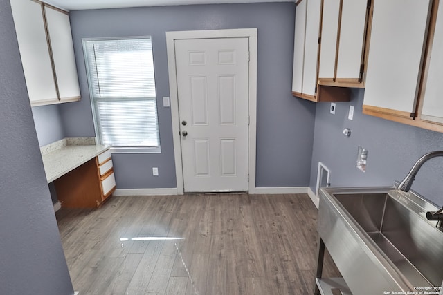 interior space with light countertops, built in study area, a sink, wood finished floors, and baseboards