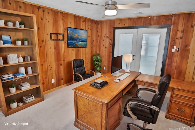 carpeted office with a ceiling fan, french doors, and wooden walls