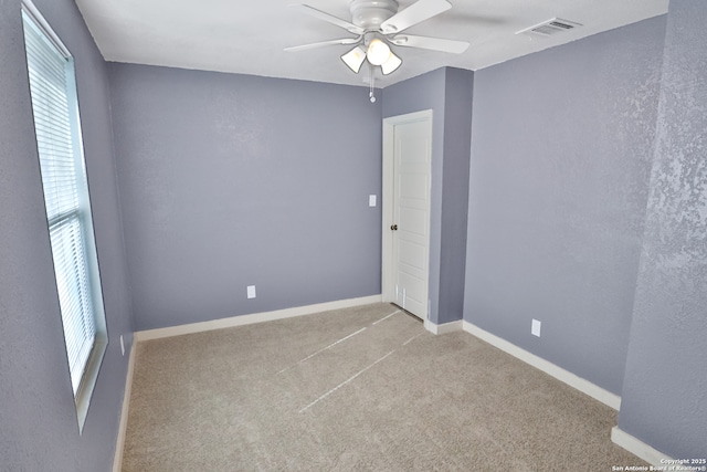 unfurnished room with baseboards, a ceiling fan, visible vents, and light colored carpet