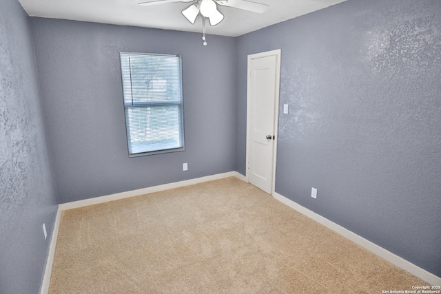 spare room with a textured wall, carpet floors, a ceiling fan, and baseboards