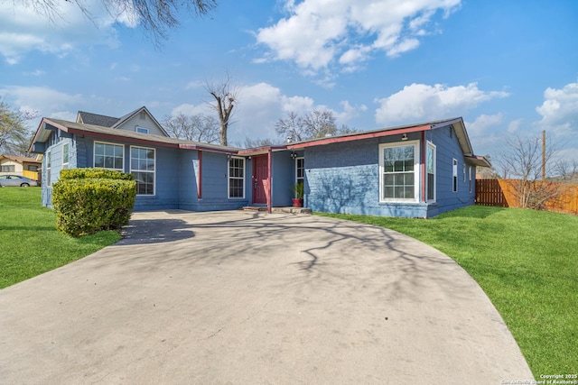 view of front of home featuring a front yard, concrete driveway, and fence