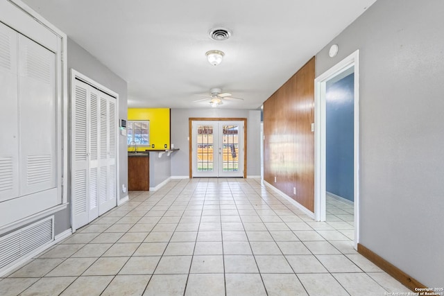 interior space with light tile patterned floors, baseboards, visible vents, a ceiling fan, and french doors