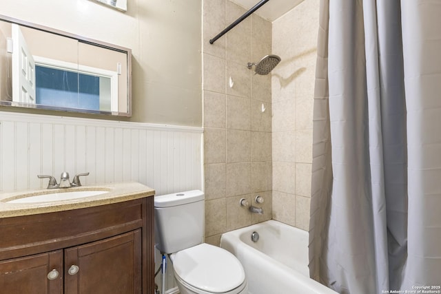 bathroom featuring toilet, a wainscoted wall, shower / bathtub combination with curtain, and vanity