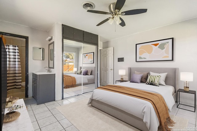 bedroom with light tile patterned flooring, a sink, visible vents, a ceiling fan, and a closet