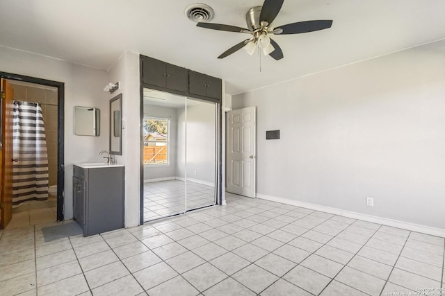 unfurnished bedroom featuring light tile patterned floors, a sink, visible vents, baseboards, and a closet