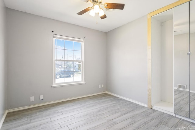 unfurnished bedroom with wood finished floors, a ceiling fan, visible vents, baseboards, and a closet