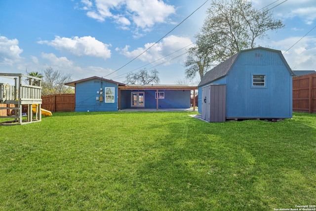 back of house featuring an outbuilding, a storage unit, a playground, and a fenced backyard