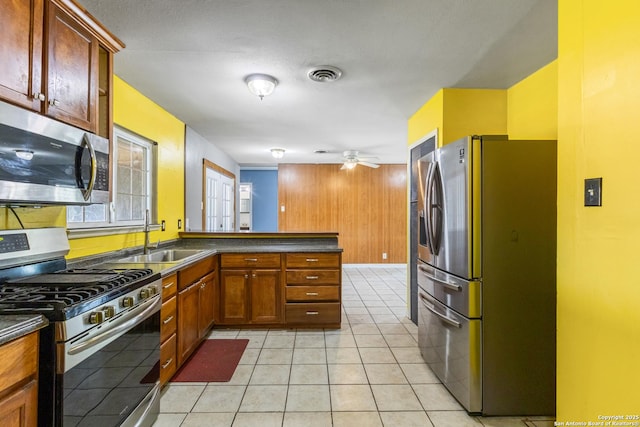 kitchen with dark countertops, visible vents, appliances with stainless steel finishes, a sink, and a peninsula