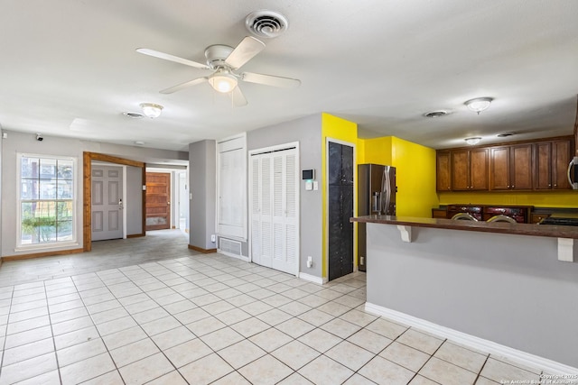 kitchen with light tile patterned floors, appliances with stainless steel finishes, dark countertops, and visible vents