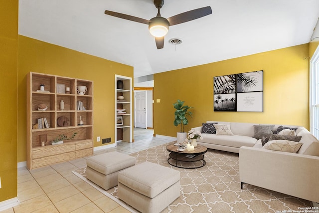 living room with built in shelves, visible vents, a ceiling fan, tile patterned flooring, and baseboards