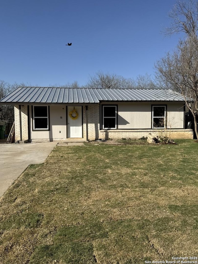 ranch-style home with metal roof, brick siding, and a front yard