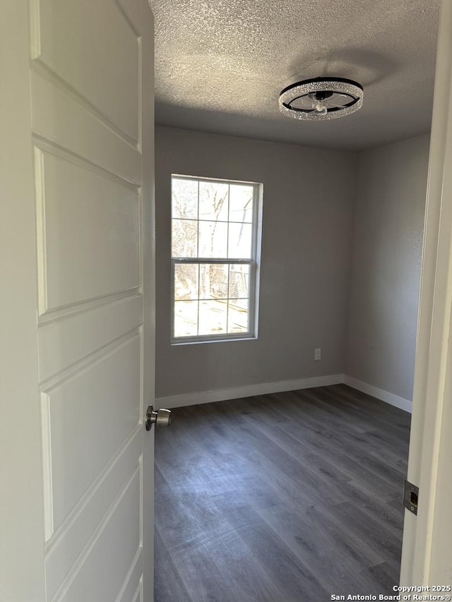 spare room with dark wood-style floors, baseboards, and a textured ceiling