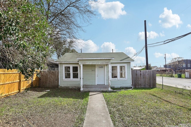 bungalow-style home featuring a fenced backyard and a front lawn