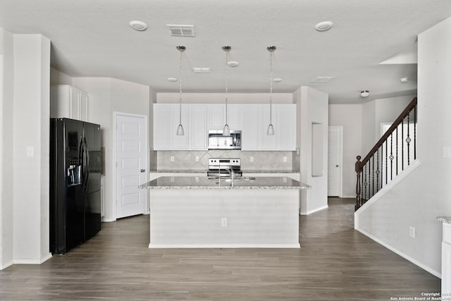 kitchen with a center island with sink, stainless steel appliances, visible vents, white cabinetry, and light stone countertops