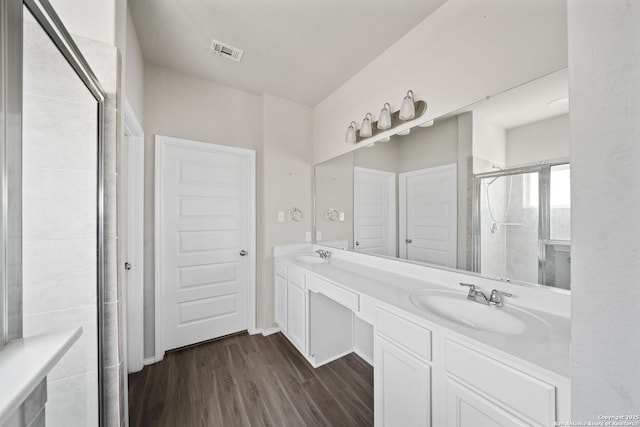 full bath with wood finished floors, a sink, visible vents, and a shower stall