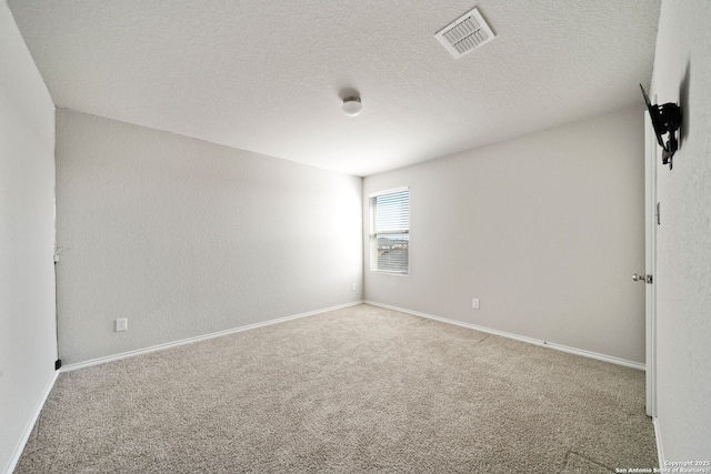 carpeted spare room featuring visible vents, a textured ceiling, and baseboards