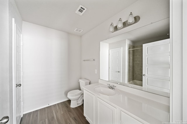 bathroom featuring toilet, vanity, wood finished floors, and visible vents