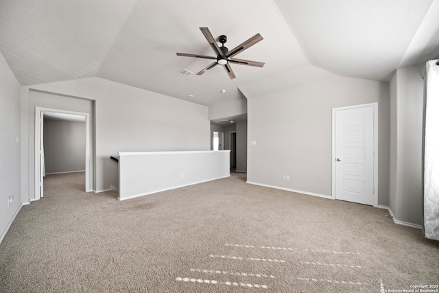 empty room featuring visible vents, baseboards, lofted ceiling, ceiling fan, and carpet