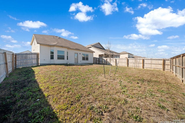 back of house with a lawn and a fenced backyard