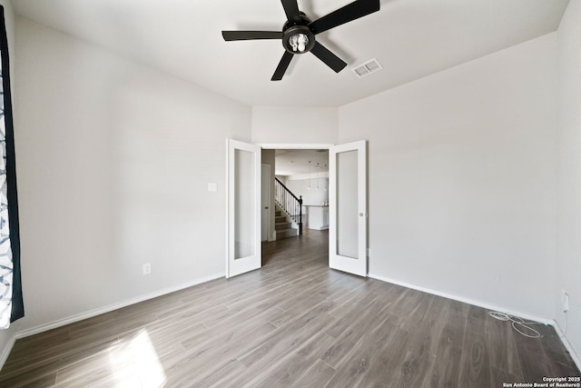 spare room with french doors, visible vents, ceiling fan, wood finished floors, and baseboards