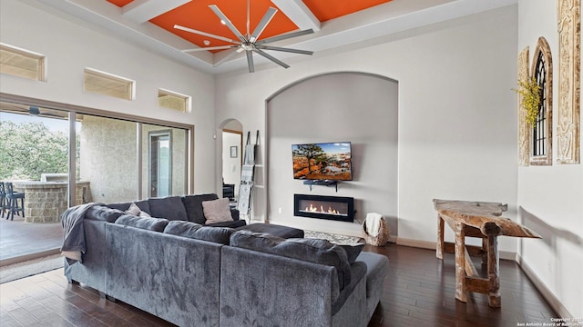 living area featuring dark wood-style floors, baseboards, coffered ceiling, and a glass covered fireplace