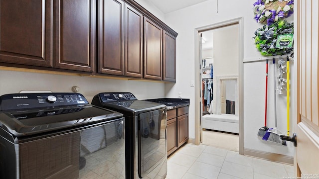 washroom with washing machine and dryer, cabinet space, baseboards, and light tile patterned flooring