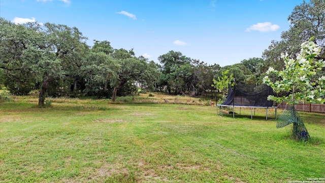 view of yard with a trampoline and fence