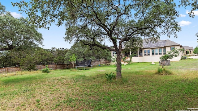 view of yard with a trampoline and fence