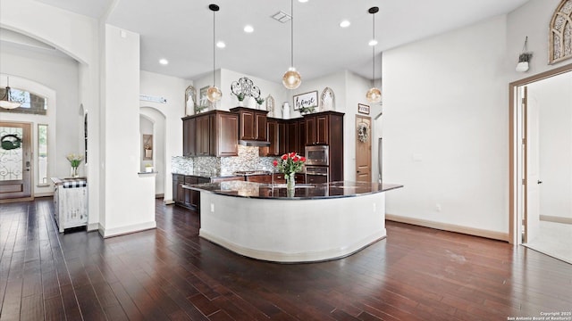 kitchen featuring stainless steel appliances, dark wood finished floors, backsplash, and dark brown cabinetry