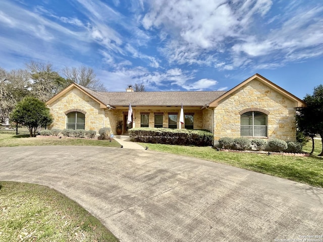 view of front of house featuring concrete driveway, a front lawn, and a chimney