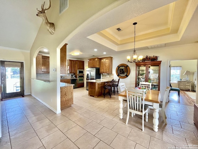 dining space with crown molding, a tray ceiling, visible vents, and a notable chandelier