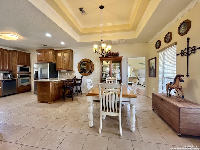 dining space featuring a chandelier, a raised ceiling, visible vents, and crown molding