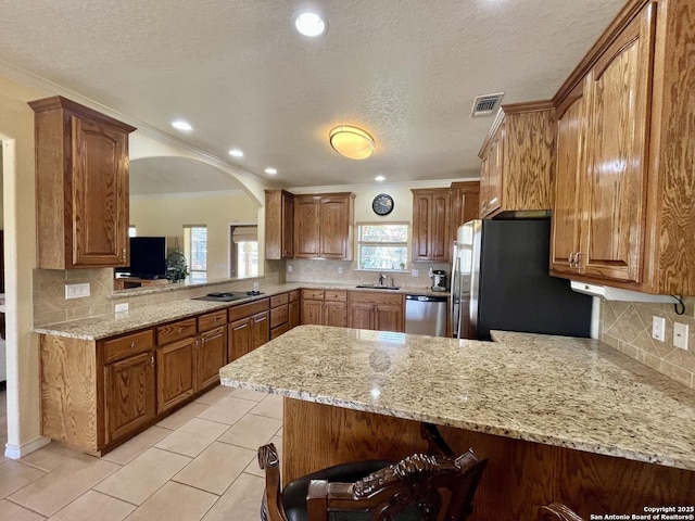 kitchen featuring visible vents, arched walkways, appliances with stainless steel finishes, a peninsula, and a sink