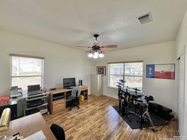 office area with baseboards, visible vents, a ceiling fan, wood finished floors, and a textured ceiling