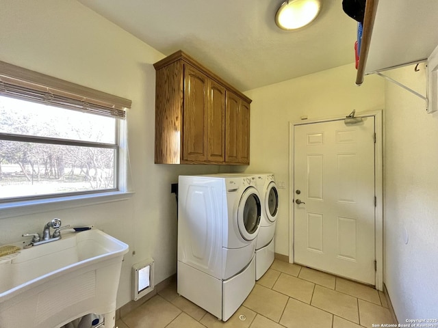 clothes washing area with light tile patterned floors, a sink, baseboards, washer and dryer, and cabinet space