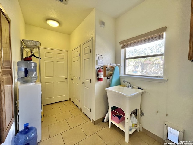 laundry room with light tile patterned flooring, a sink, and baseboards