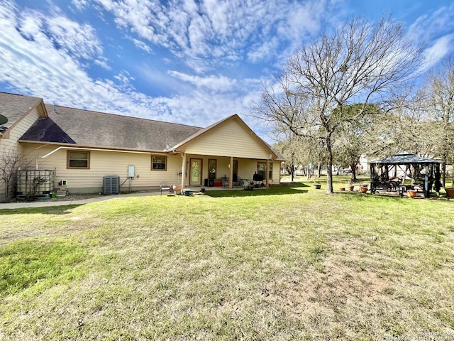 rear view of property with roof with shingles, central air condition unit, a lawn, a gazebo, and a patio area