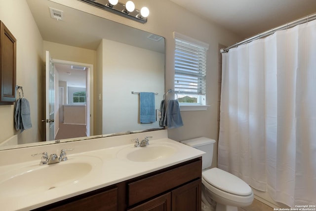 full bath with visible vents, a sink, toilet, and double vanity