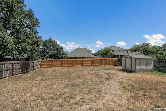 view of yard featuring a fenced backyard, a storage unit, and an outbuilding