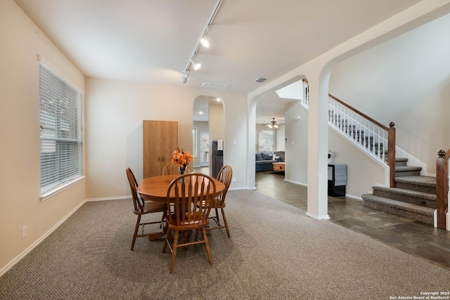 dining room featuring baseboards, arched walkways, stairway, carpet floors, and track lighting