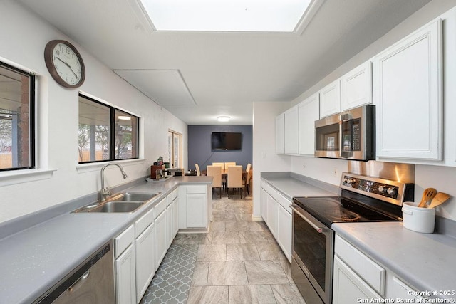 kitchen with appliances with stainless steel finishes, light countertops, white cabinets, and a sink