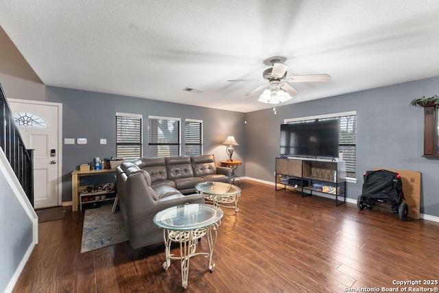 living area featuring visible vents, a ceiling fan, wood finished floors, baseboards, and stairs