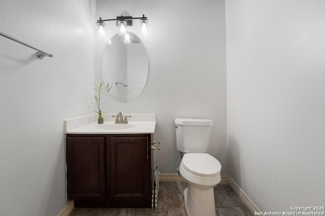 bathroom with toilet, baseboards, and vanity