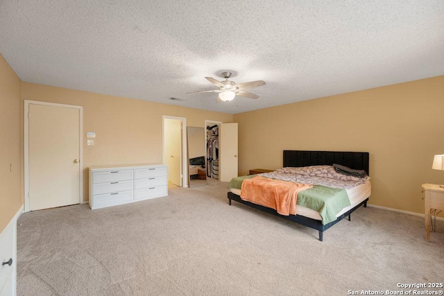 bedroom with a textured ceiling, carpet flooring, visible vents, a ceiling fan, and a spacious closet